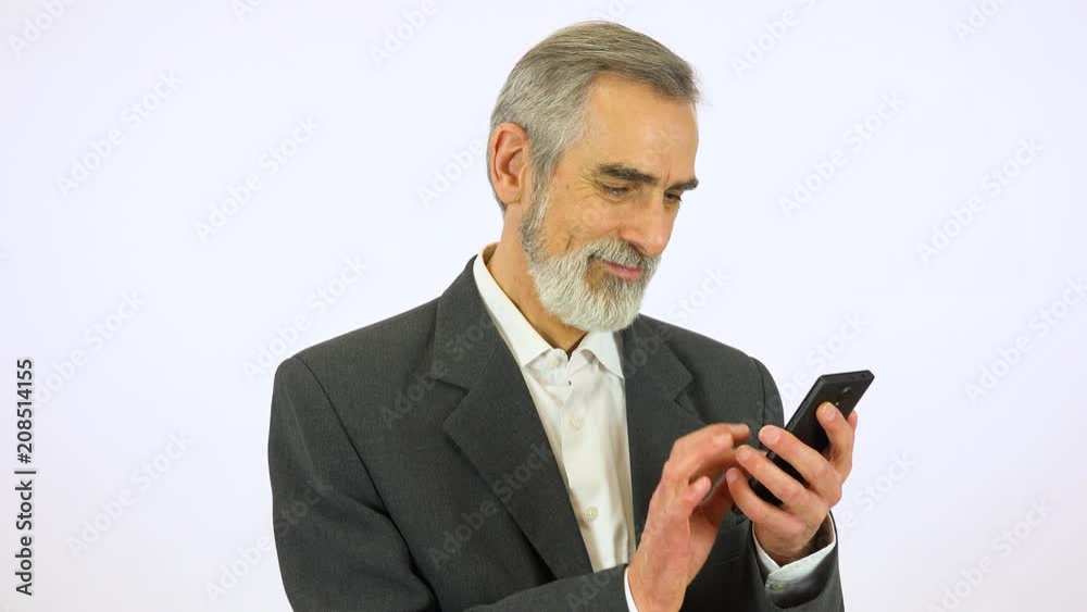An elderly man works on a smartphone with a smile - white screen studio An elderly man works on a smartphone with a smile - white screen studio