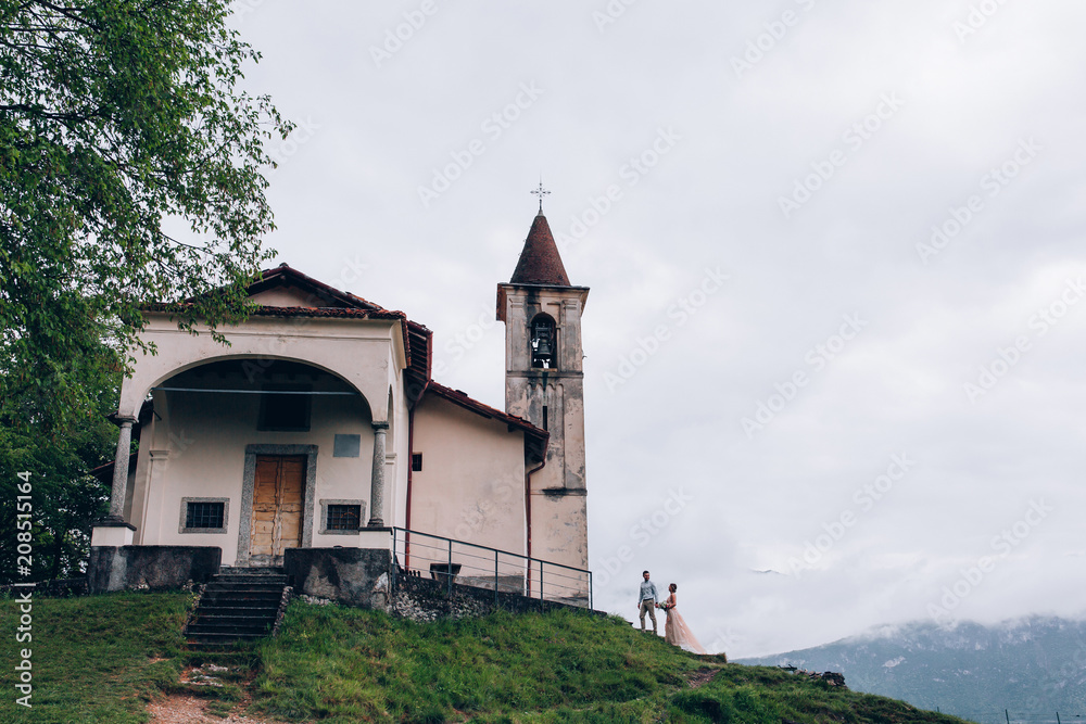 Walking newlyweds in nature. Groom and bride against the background of the church.
