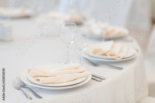 Festive table setting at a banquet in white. White plates, napkins and tablecloth in a restaurant