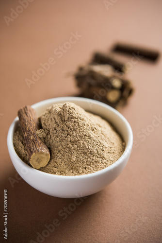 Ayurvedic Mulethi or Liquorice root stick or jeshthamadh powder served in a bowl over moody background