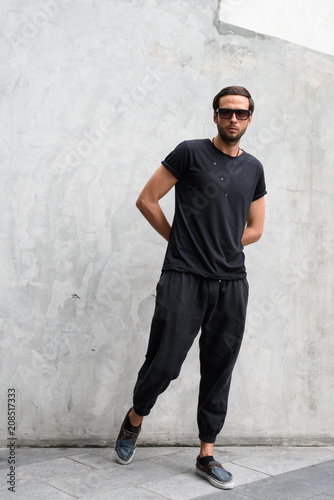 Handsome man wearing sunglasses against concrete wall in the str