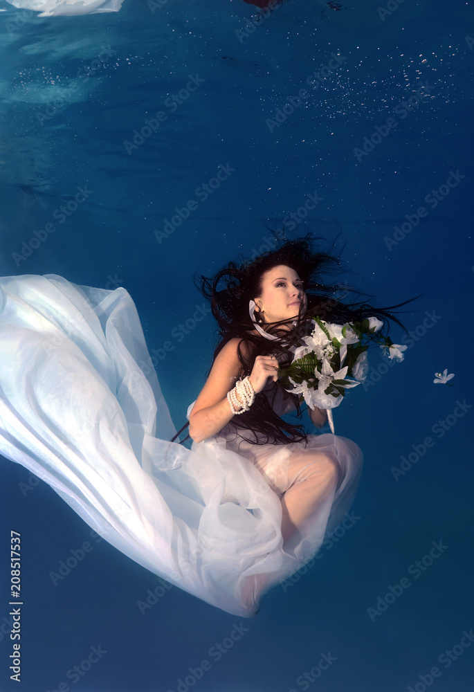 Bride in a wedding  with flowers underwater in the pool. Underwater wedding