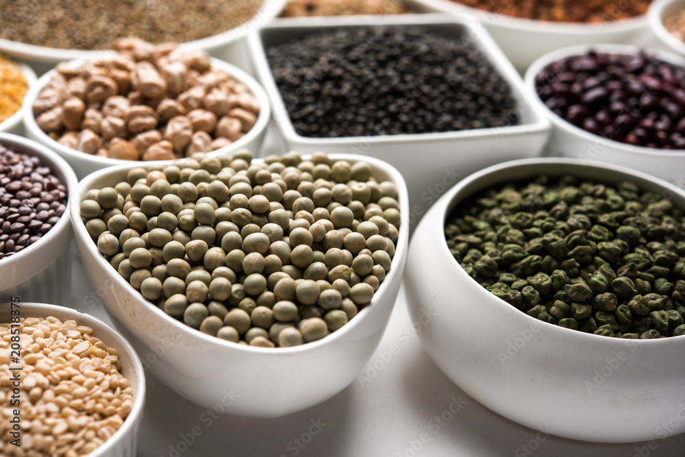 Uncooked pulses,grains and seeds in White bowls over white background. selective focus