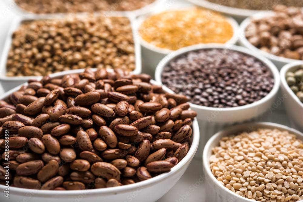 Uncooked pulses,grains and seeds in White bowls over white background. selective focus Uncooked pulses,grains and seeds in White bowls over white background. selective focus