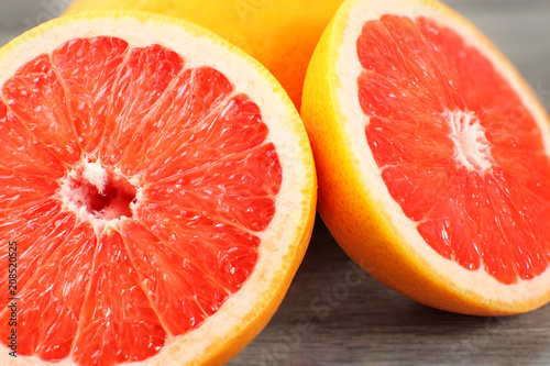 Fotografía Closeup of pink grapefruit cut in half, on gray wood desk.