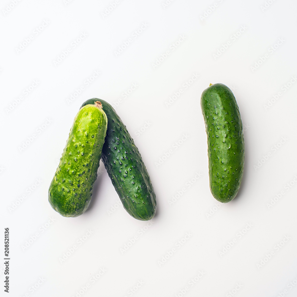 Green vegetables flat lay concept. Cucumber on white background, top view with empty space for text. Green vegetables flat lay concept. Cucumber on white background, top view with empty space for text.
