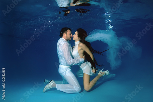 The bride and groom kiss underwater in the pool. Underwater wedding photo