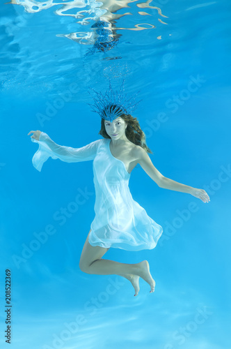 The Snow Queen - The young beautiful woman in a crown and white dress posing under water (for calendar, winter, January)