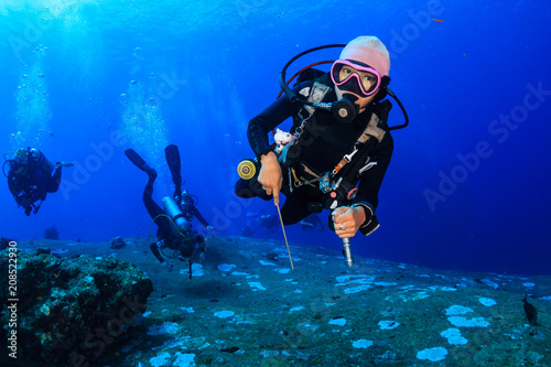 Female SCUBA diver swimming over a colorful, healthy tropical coral reef