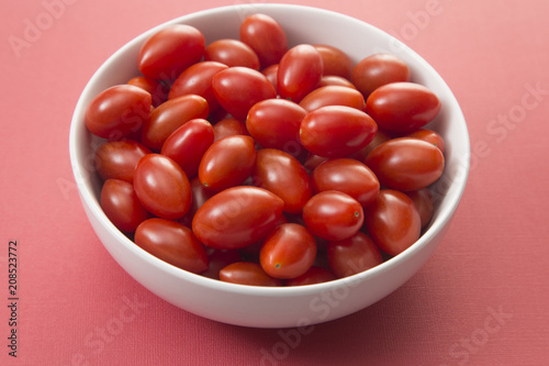 Grape Tomatoes in a White Bowl on a Red Background photo