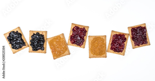 Some dry biscuits with jam on a white surface