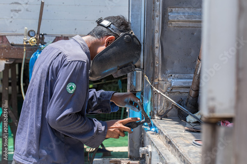 Welding in the industry by highly skilled technicians and wearing a safety mask.
