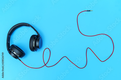 Black headphone and red cable on a blue background, Used in decoration and design.