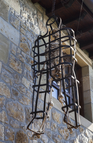 The skeleton of a man in a metal old torture  cage. 