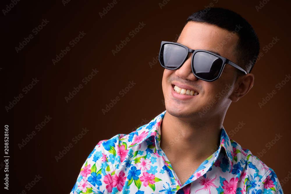 Young multi-ethnic Asian tourist man against brown background Young multi-ethnic Asian tourist man against brown background