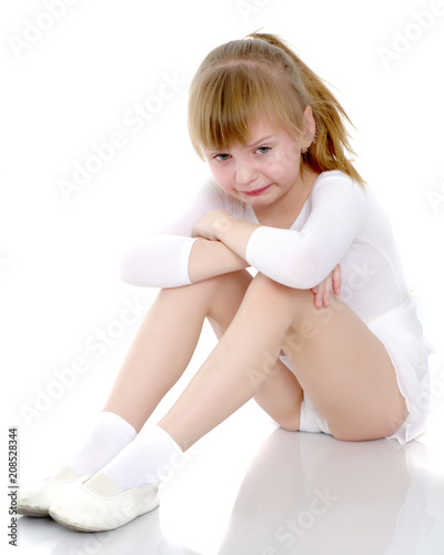 Girl gymnast sits on the floor and cries
