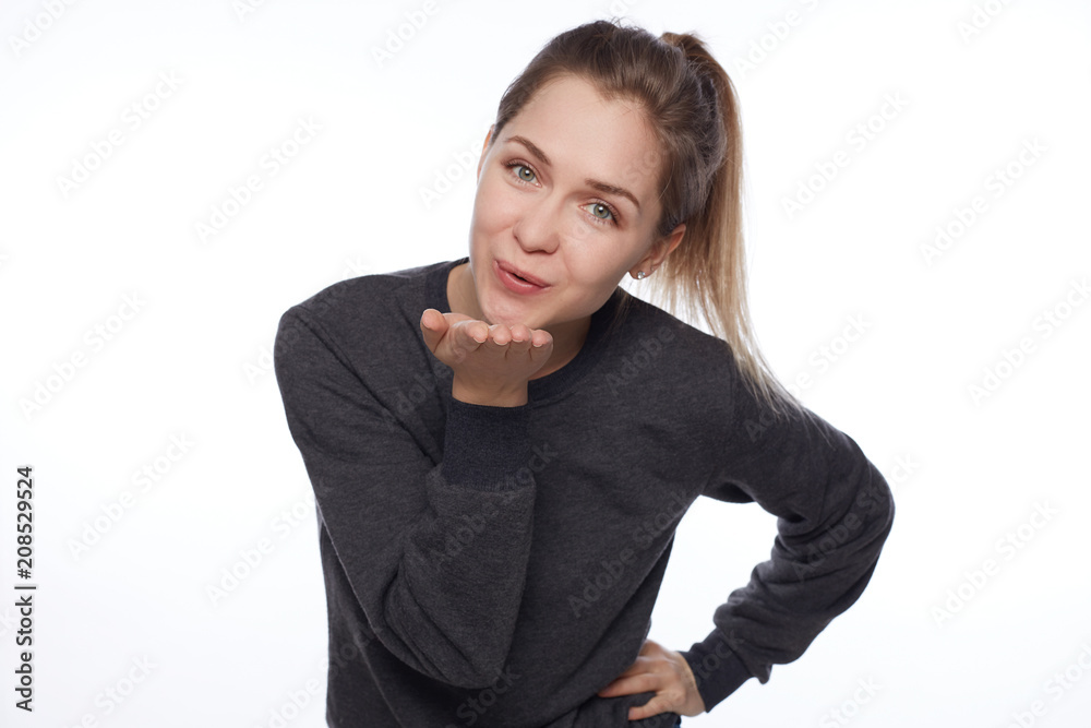 Attractive young woman with makeup and long blonde hair blows kiss, demonstrates her good feelings, says goodbye on distance, isolated over white background. Young pretty female model makes air kiss. Attractive young woman with makeup and long blonde hair blows kiss, demonstrates her good feelings, says goodbye on distance, isolated over white background. Young pretty female model makes air kiss.