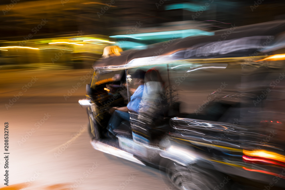 Tuk tuk taxi turning left at night in the streets of Chiang Mai in northern Thailand