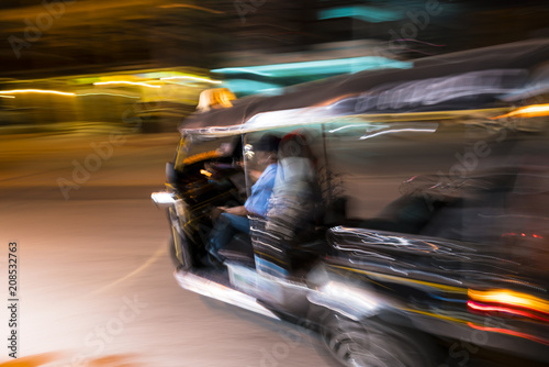 Tuk tuk taxi turning left at night in the streets of Chiang Mai in northern Thailand