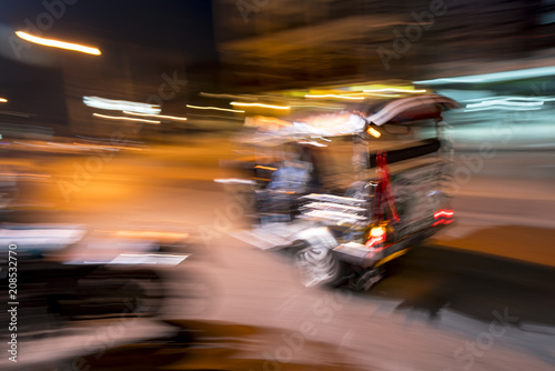 Tuk tuk racing past at night in the streets of Chiang Mai in northern Thailand
