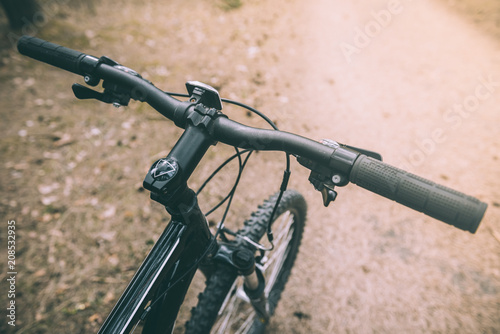 Mountain biking down hill descending fast on bicycle. View from bikers eyes. Close up bicycle handlebar.