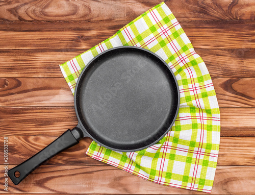 Frying pan with kitchen towel on the wooden table. Top view.