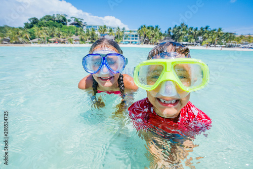 Two happy kids in diving masks having fun on the beach