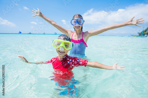 Two happy kids in diving masks having fun on the beach