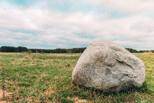 Belarusian landscape with a boulder in the center field. Sunset landscape.