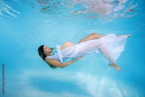 Young pregnant woman in a bikini under water in the pool photo