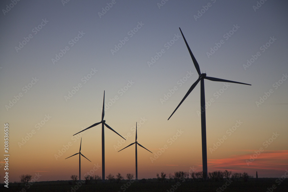 Wind energy turbines on sunset sky background, Energy generator nature friendly.