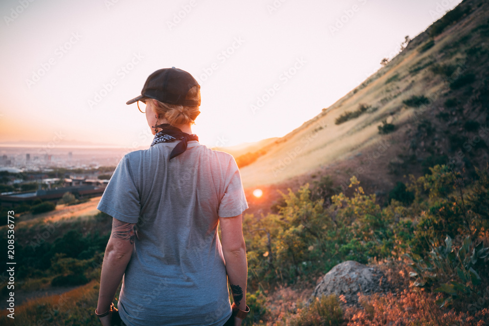 Naklejka premium Girl hiking and looking at sunset