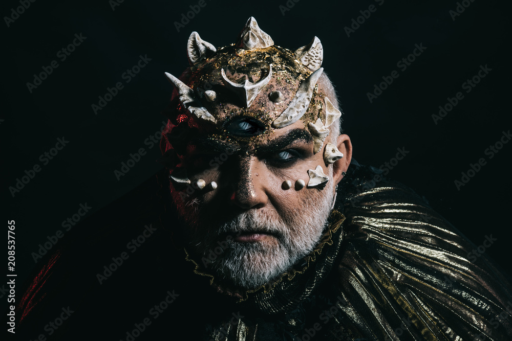 Alien, demon, sorcerer makeup. Man with third eye, thorns or warts. Demon  on black background, copy space. Horror and fantasy concept. Senior man  with white beard dressed like monster in darkness Stock