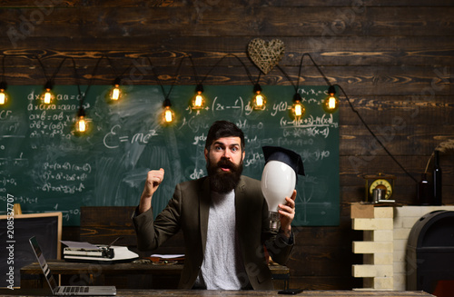 Genius man with beard hold bulb on chalkboard. Genius businessman with lightbulb got idea in classroom, enlightenment