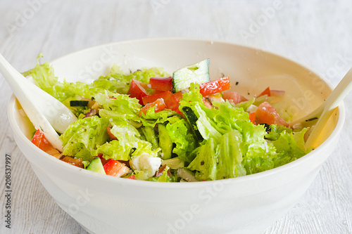 bowl of salad with vegetables and greens on wooden table
