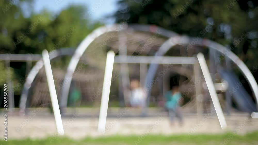 Out focus of two happy children ride on a swing at summer park. Cute teen boy and girl swings at playground outdoors. Out focus of two happy children ride on a swing at summer park. Cute teen boy and girl swings at playground outdoors.