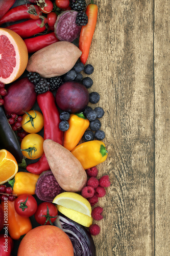 Health food fruit and vegetable background border on rustic wood background. Super  foods for healthy eating and high in antioxidants, anthocyanins, vitamins and minerals. Top view.
