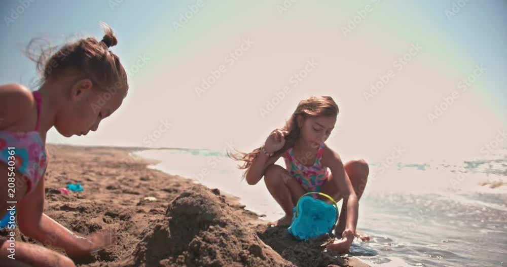 Multi-ethnic adopted children playing with toys on beach sand