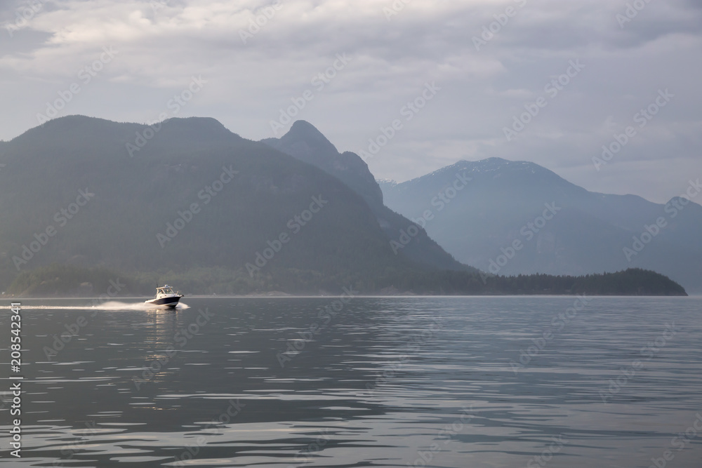 Speed boat in the ocean surrounded by the Canadian Mountain Landscape. Taken in Howe Sound, North of Vancouver, British Columbia, Canada. Speed boat in the ocean surrounded by the Canadian Mountain Landscape. Taken in Howe Sound, North of Vancouver, British Columbia, Canada.