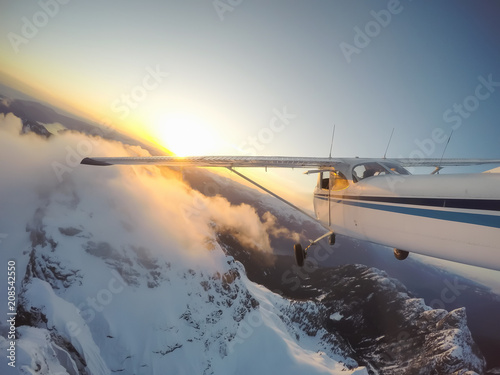 Airplane flying over the beautiful Canadian Landscape during a vibrant and colorful sunset. Taken near Vancouver, British Columbia, Canada.