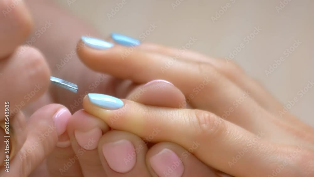 Nail salon manicure workshop. Female manicure master applies blue color polish gel on healthy woman nails. Skin and nails care concept. Nail salon manicure workshop. Female manicure master applies blue color polish gel on healthy woman nails. Skin and nails care concept.
