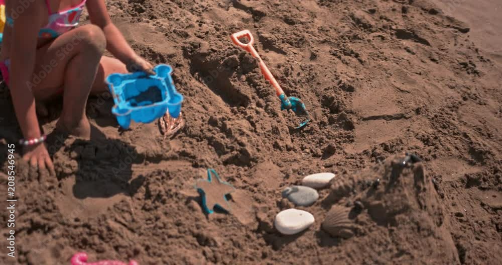 Young girl playing with toys on beach sand in summer Young girl playing with toys on beach sand in summer