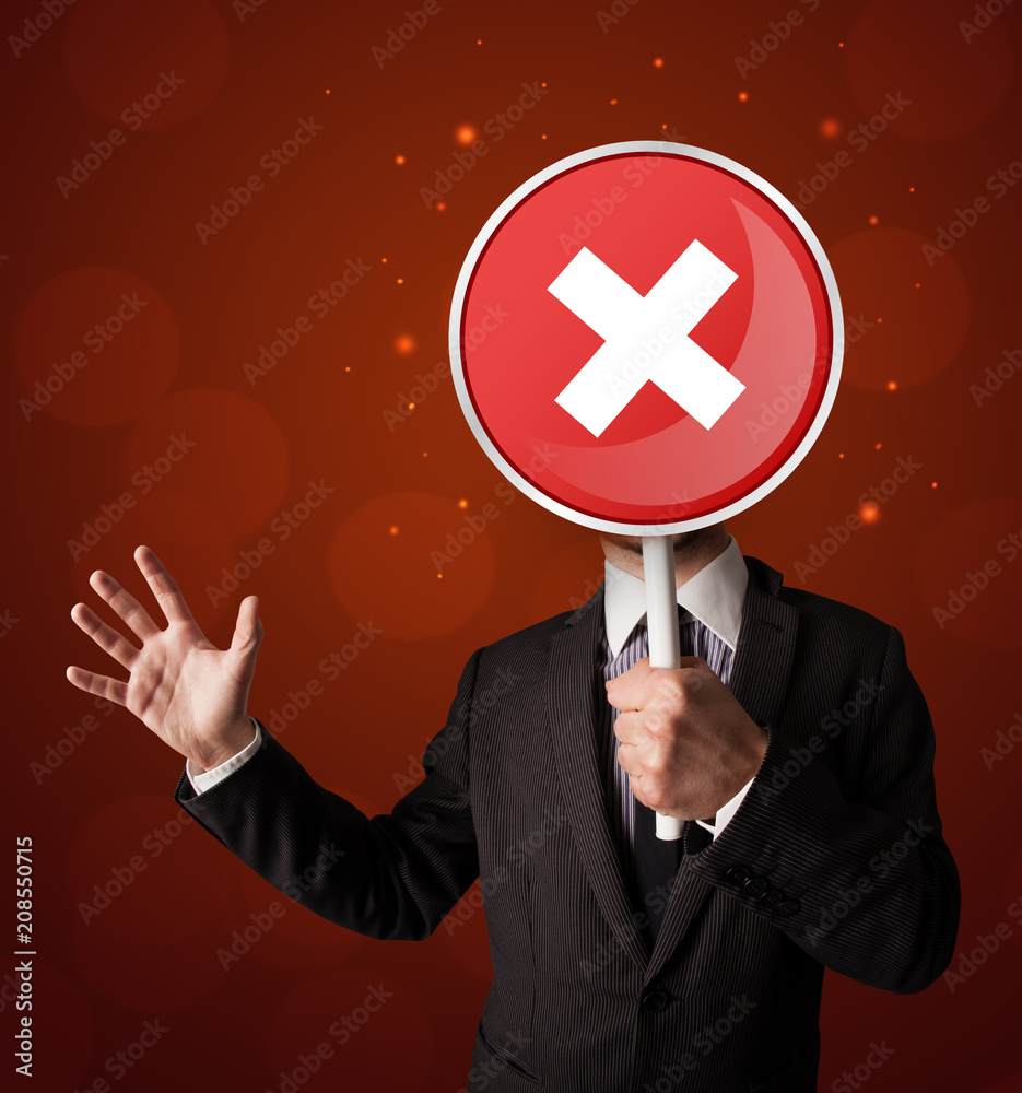Smart businessman holding round red sign with a white cross Smart businessman holding round red sign with a white cross
