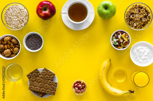 Ideas of healthy hearty breakfast for sportsmen. Fruits, oatmeal, yogurt, nuts, crispbreads, chia on yellow background top view copy space