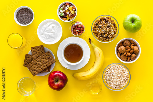 Layout of products for healthy and hearty breakfast. Fruits  oatmeal  yogurt  nuts  crispbreads  chia on yellow background top view copy space
