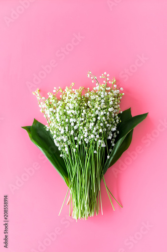 May flowers. Bouqet of lily of the valley flowers on pastel pink background top view copy space