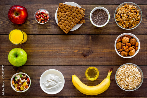 Set of products for healthy vegetarian breakfast. Fruits, oatmeal, yogurt, nuts, crispbreads, chia on dark wooden background top view space for text