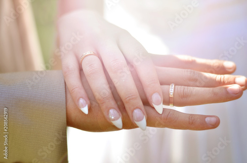 Hands with the wedding rings at sunset. The hands of the bride and groom with rings.