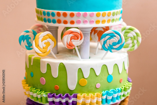 Beautiful multi-colored children's cake from several layers decorated with sweets. photo