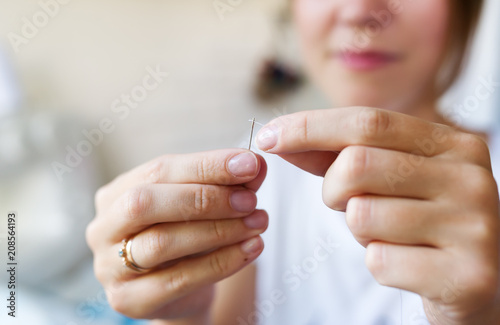 Seamstress threading a needle.